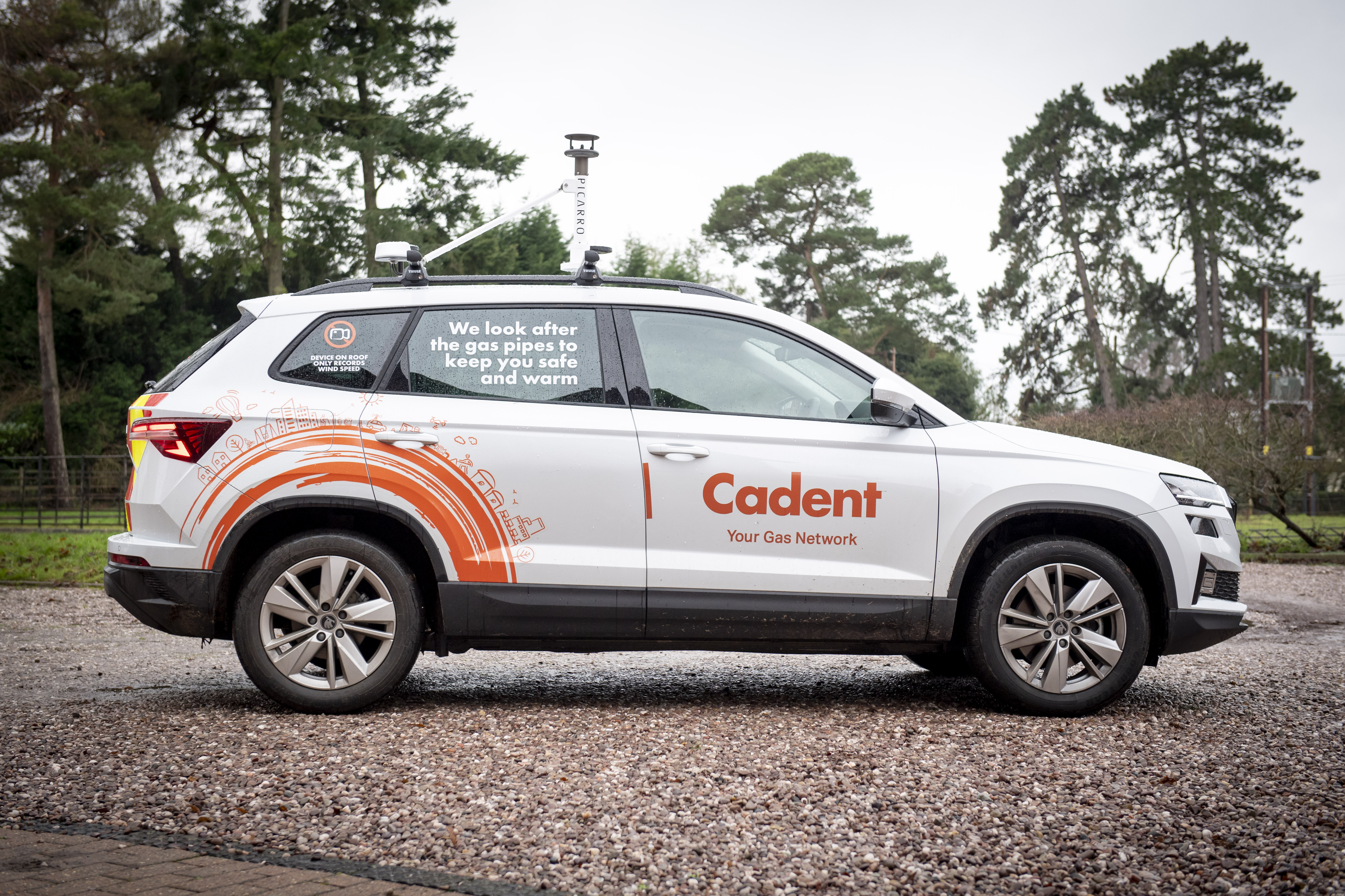 Rear of a Cadent utility vehicle showing a sticker that reads 'Device on roof only records wind speed' with a camera icon