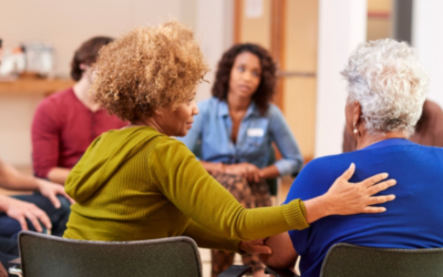 A diverse group of people sits in a circle, engaged in a supportive discussion