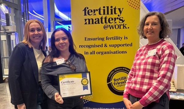 Three colleagues with the Fertility employer award and the fertility matters at work banner in background