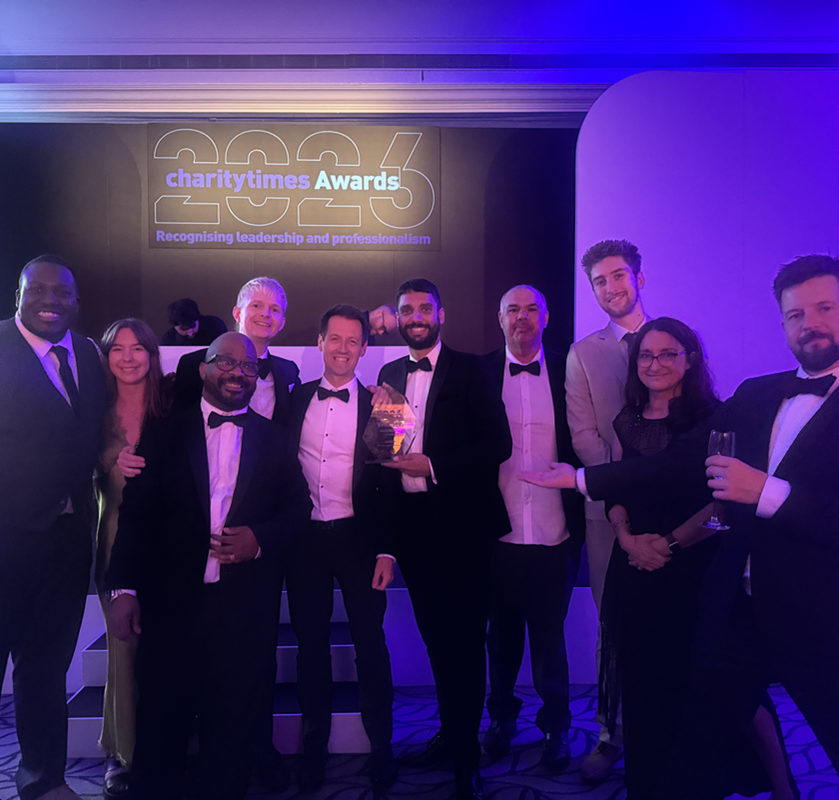 group photo of the Cadent and Groundwork partnership team at the Charity Times Awards ceremony, standing on stage beneath a Charity Times Awards sign and holding the Charity Collaboration of the Year award for the Stay Warm, Stay Well programme.