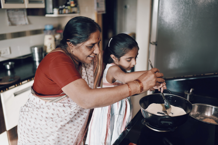 Two people cooking together in a kitchen, stirring ingredients in a pot on the stove.