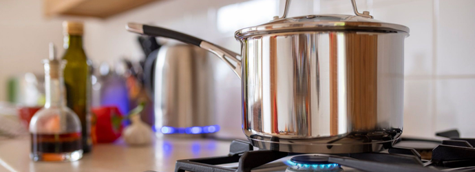 Close-up side-view shot of a cooking pot on a gas stove. Using a single ring to save extra cost of using gas as current energy prices increase. /