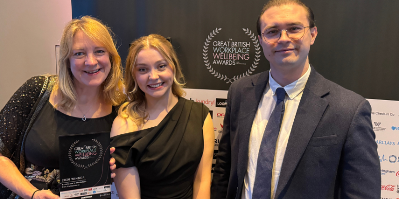 Cadent team receiving an award at The Great British Workplace Wellbeing Awards, standing in front of the event backdrop.