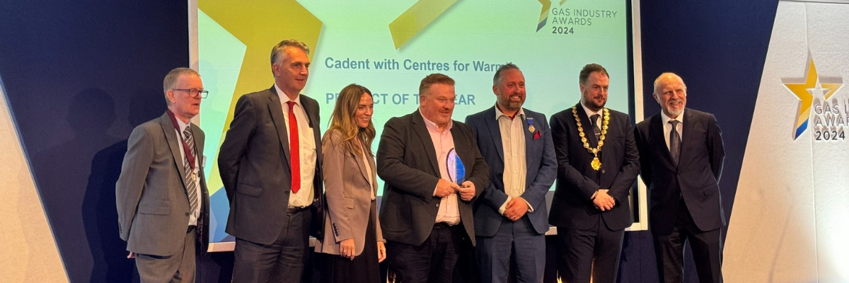 A Group of people on stage posing for a photoshoot on an award ceremony with a trophy on hand being displayed.