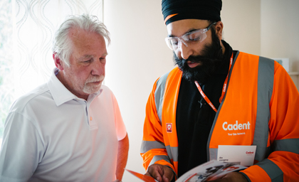 Cadent engineer in orange safety jacket showing a brochure to a customer indoors
