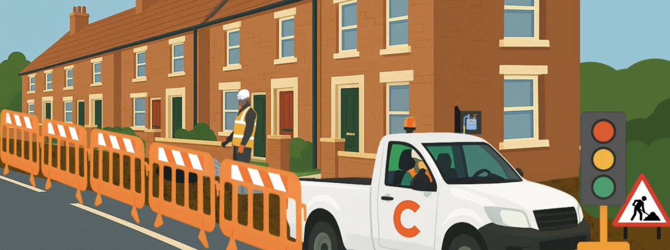 A construction worker, stands near orange barriers on a residential street. A white truck with a Cadent logo.